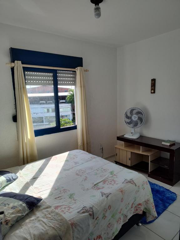 a bedroom with a bed and a window with a fan at A Felicidade Mora Aqui!!!! in Novo Hamburgo