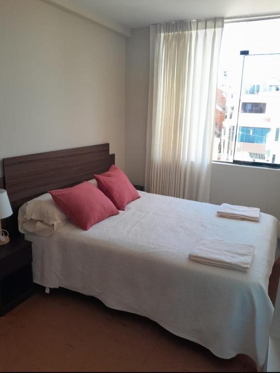 a bedroom with a bed with red pillows and a window at Las Mercedes in Arequipa