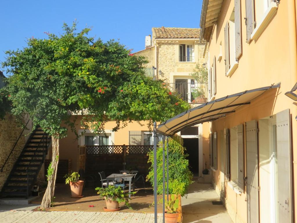 ein Gebäude mit einem Baum und einem Tisch im Innenhof in der Unterkunft Maison d'hôtes La Bignone in Laudun