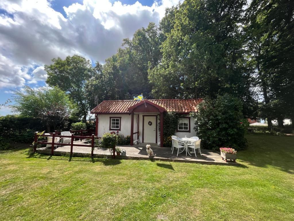 ein kleines Haus mit einer Terrasse im Hof in der Unterkunft Åkarpsvägen Vacation Home in Trelleborg