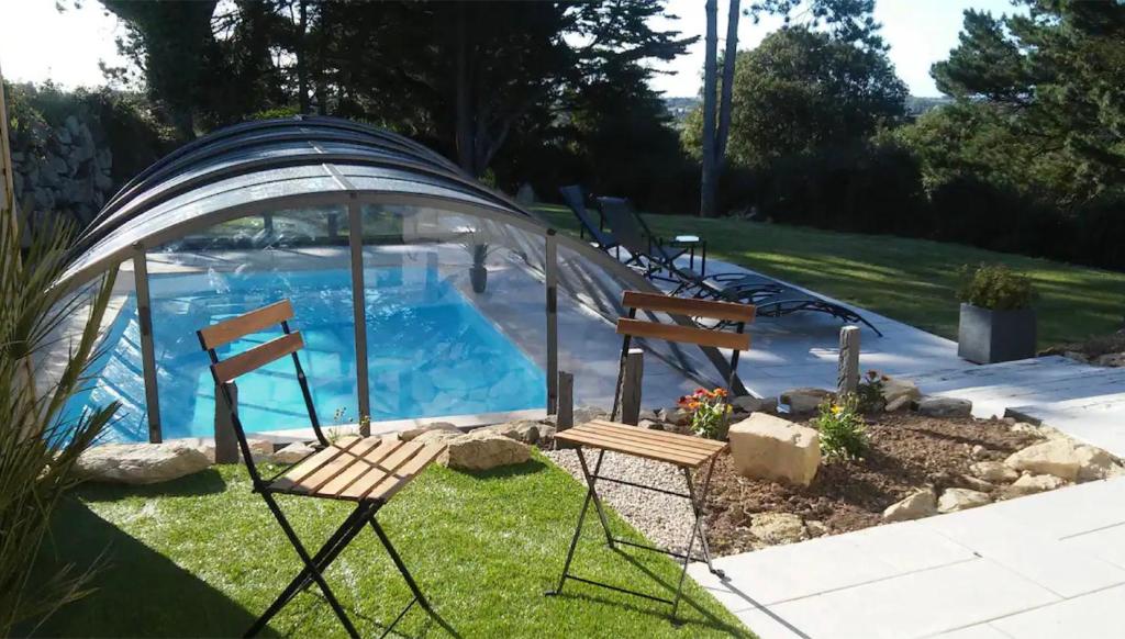 um par de cadeiras em frente a uma piscina em Maison vue mer avec piscine em Plouider