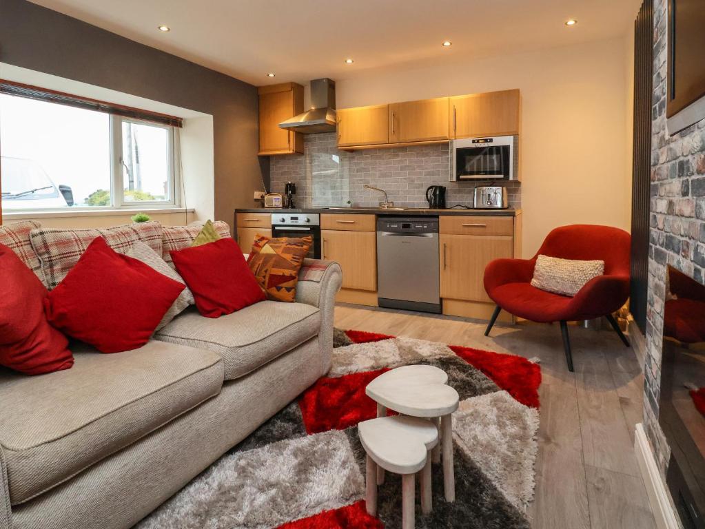 a living room with a couch and a kitchen at 2 Stoneleigh Cottage in Wrexham