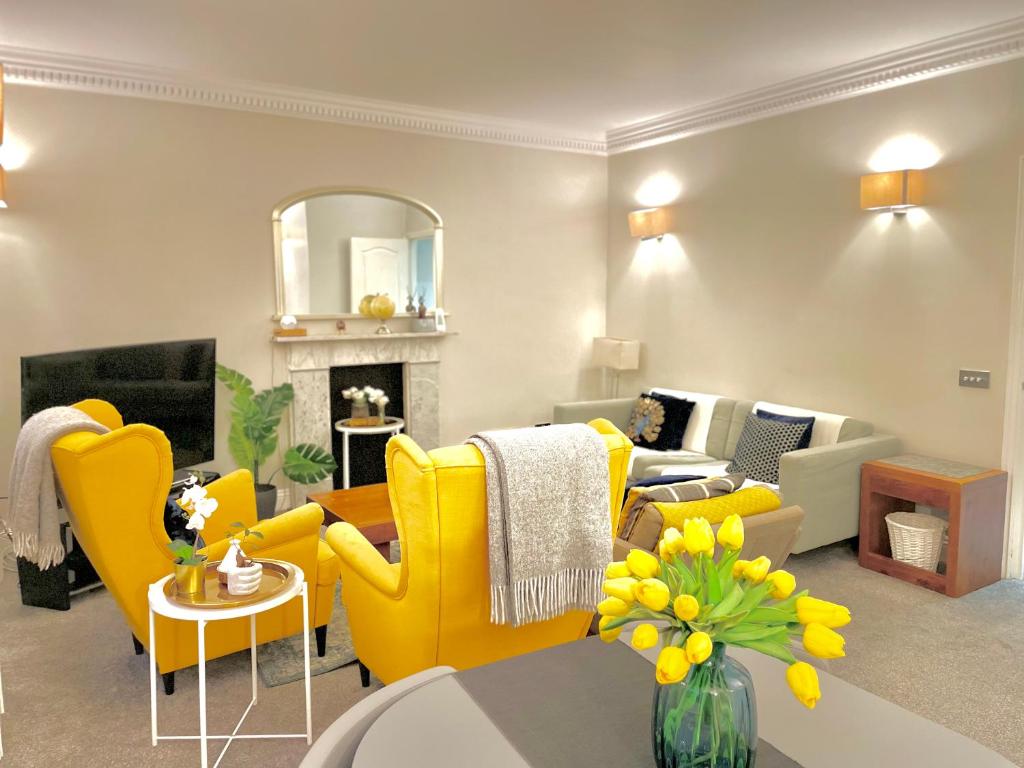 a living room with yellow chairs and a fireplace at Beaufort Gardens Apartment in Knightsbridge in London