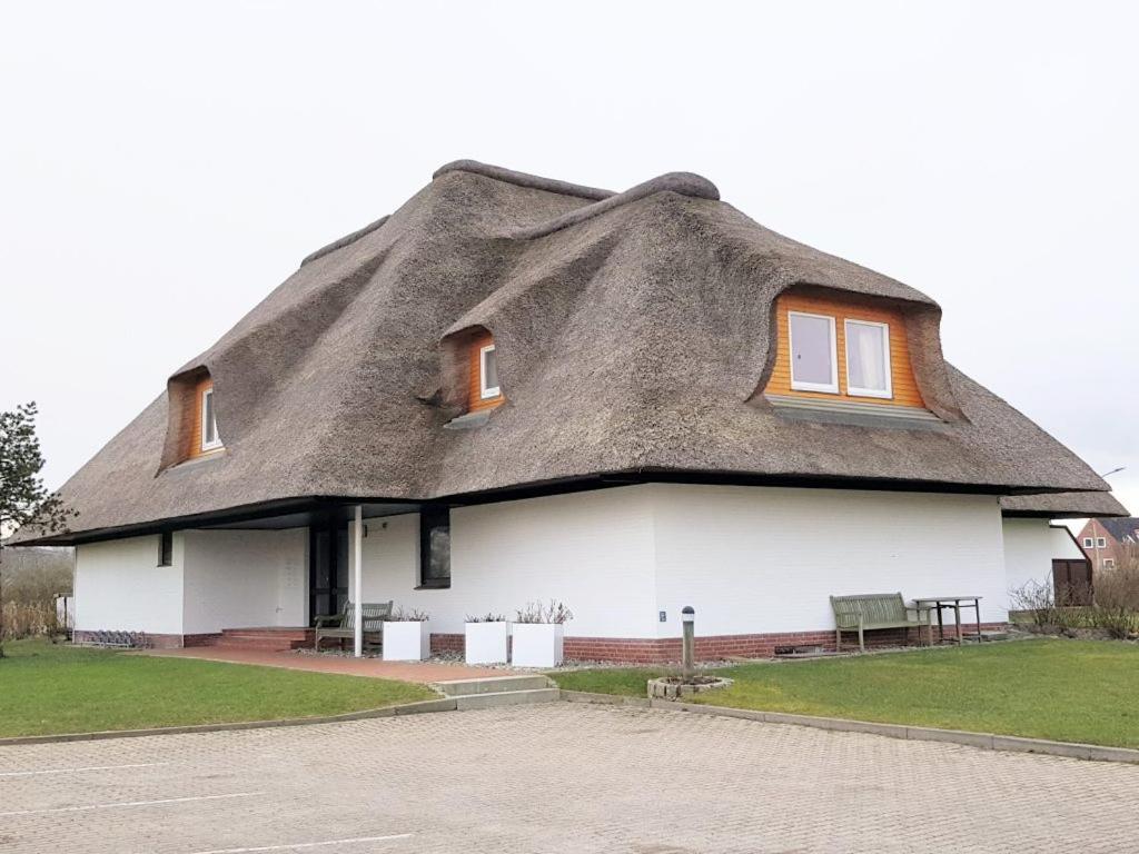a thatched roof house with a bench in front at to the Beach in Brösum