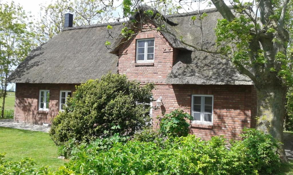 uma antiga casa de tijolos com telhado de palha em Friesenhus em Katingsiel