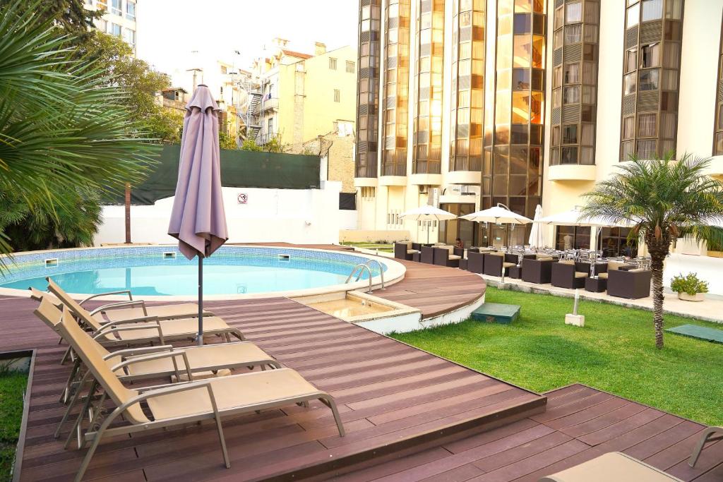 eine Terrasse mit Stühlen, einem Sonnenschirm und einem Pool in der Unterkunft Legendary Lisboa Suites in Lissabon