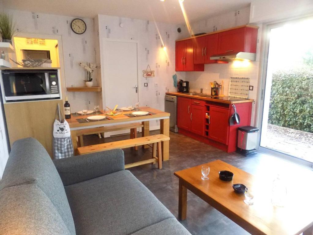 een woonkamer met een bank en een keuken met rode kasten bij Saint Georges de Didonne - APPARTEMENT en rez-de-chaussée - proche PLAGE in Saint-Georges-de-Didonne