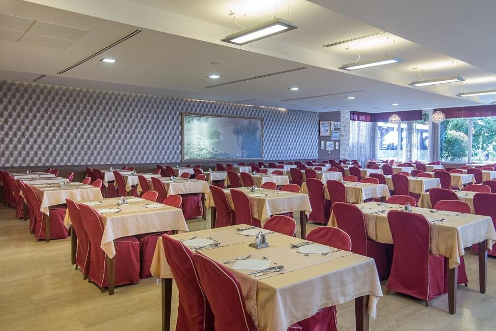 a banquet hall with tables and red chairs and a screen at Hotel Palas in Petrovac na Moru