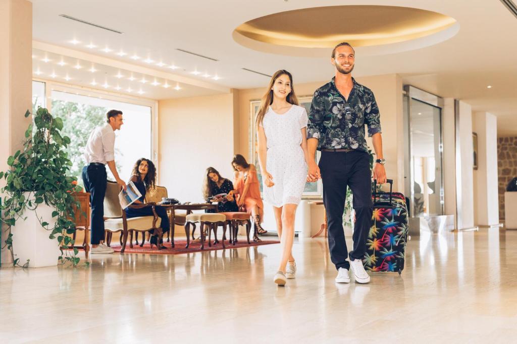 a man and a woman walking through a lobby at Hotel Palas in Petrovac na Moru