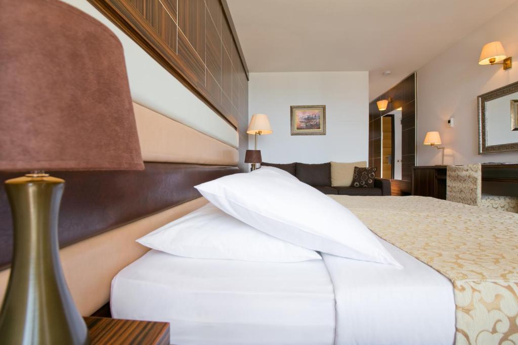 a hotel room with a bed with white pillows at Hotel Palas in Petrovac na Moru