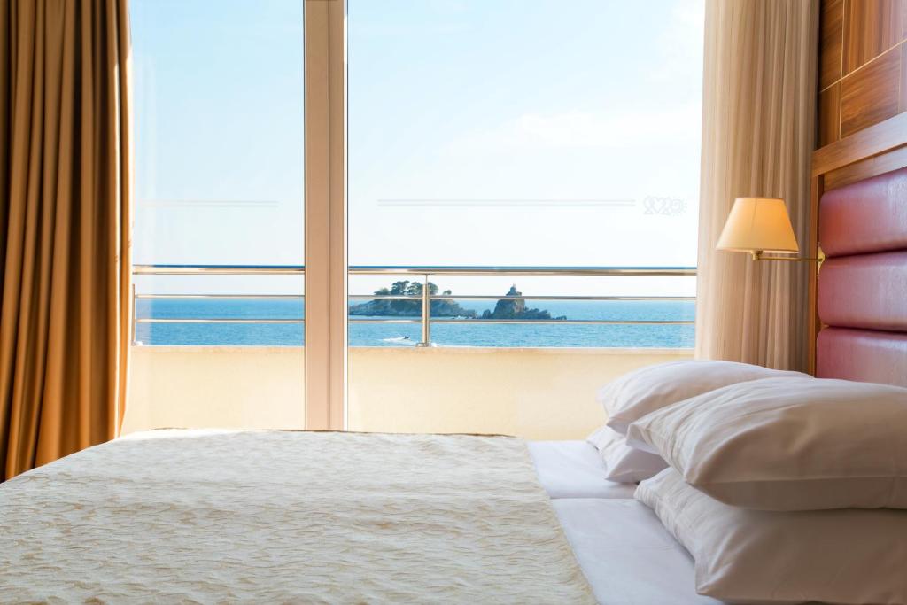 a bedroom with a large window with a view of the ocean at Hotel Palas in Petrovac na Moru