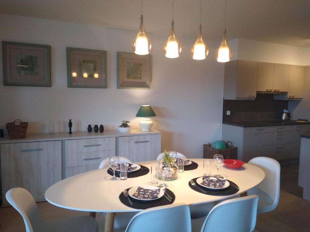 una cocina con una mesa blanca con sillas y luces en Duin en zee, en Bredene