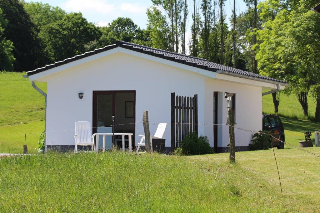 a small white cottage in a field at Ferienhaus Ostseeblick in Munkbrarup