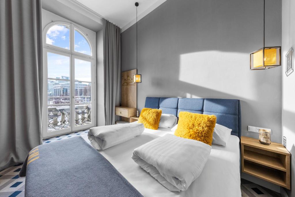 ウィーンにあるKH Opera Apartmentsの黄色い枕と窓のあるベッドのある寝室