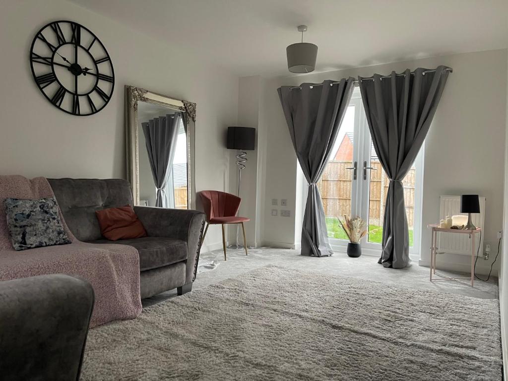 a living room with a couch and a clock on the wall at Walsall New Large House with Garden in Pelsall