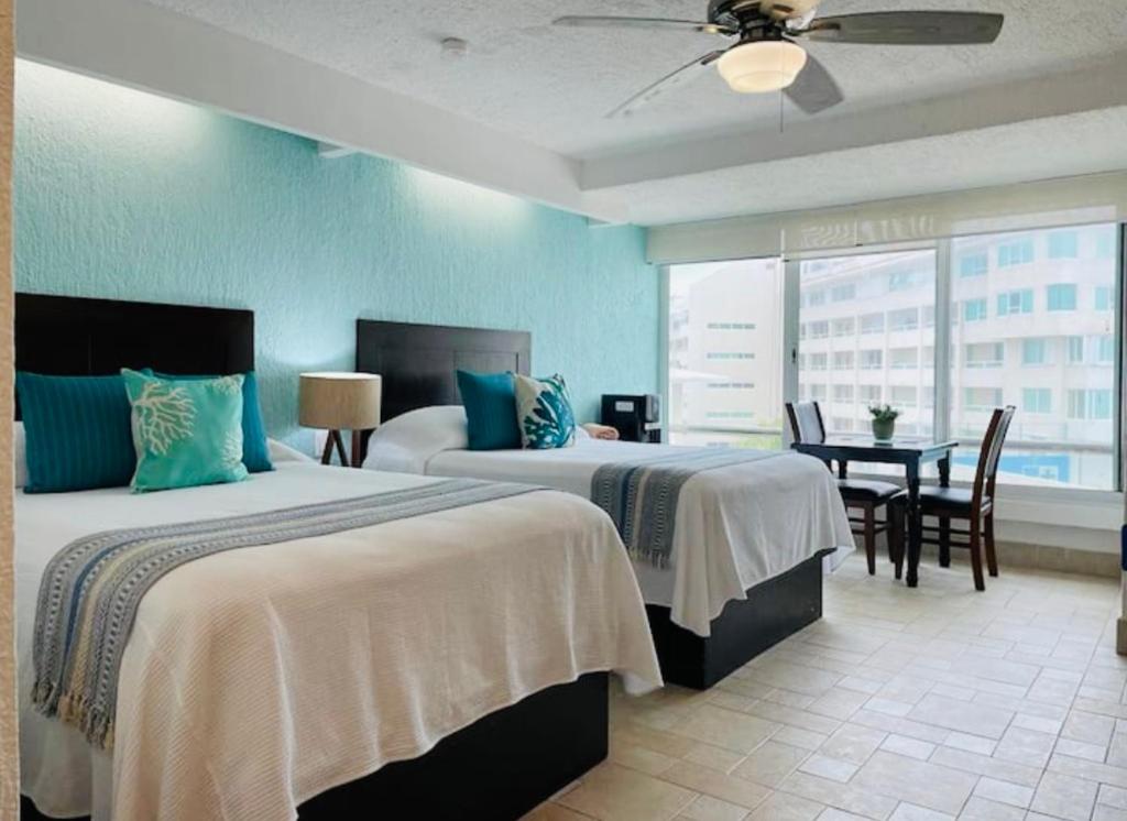 Cette chambre d'hôtel comprend deux lits, une table et des chaises. dans l'établissement Cancun Studio overlooking the Lagoon, à Cancún
