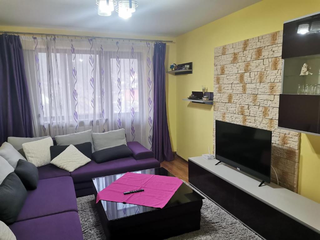 a living room with a purple couch and a tv at Apartament Sofia in Sovata