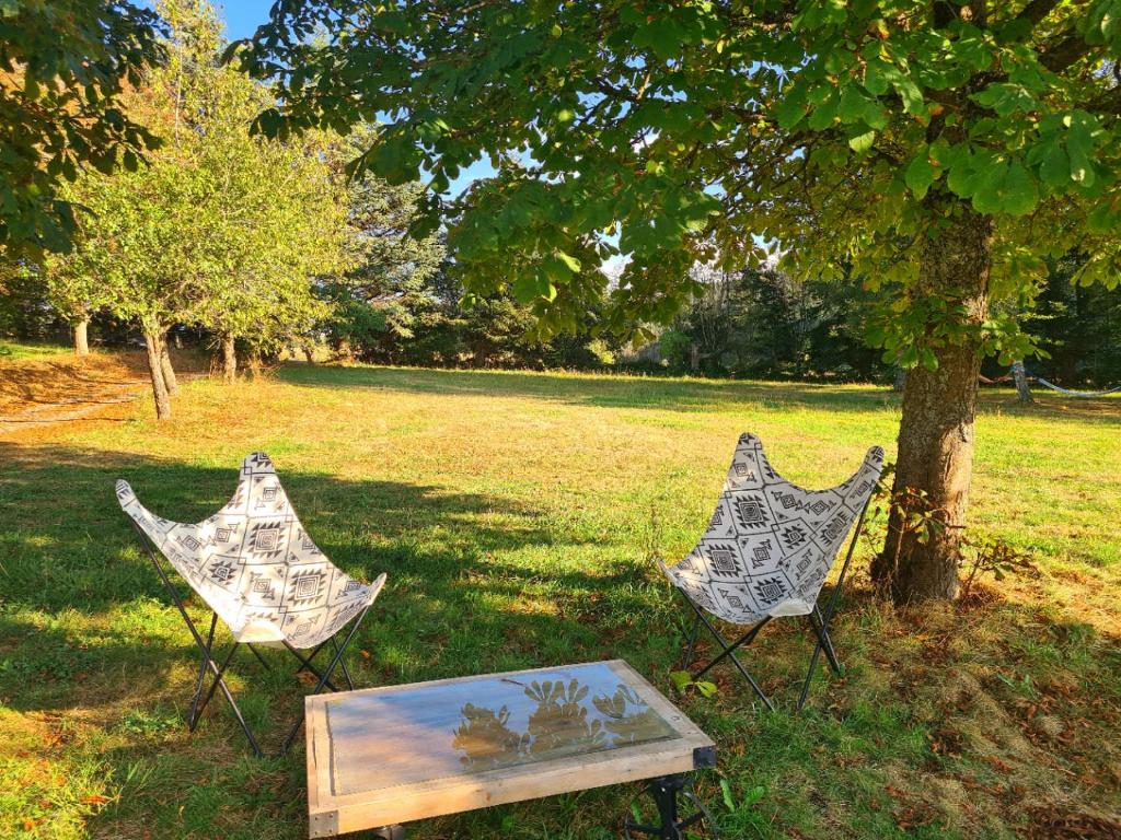 dos sillas y una mesa junto a un árbol en Room lover Les Chaizes, en Saint-Romain-Lachalm