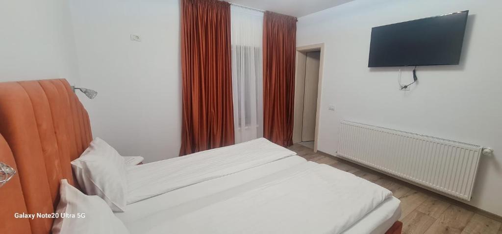 a bedroom with a white bed and a flat screen tv at LukAmi Green Home in Făgăraş