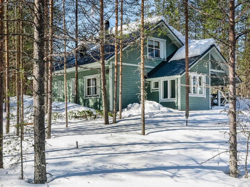 een groen huis in de sneeuw met bomen bij Holiday Home Huuhkalinna by Interhome in Syöte