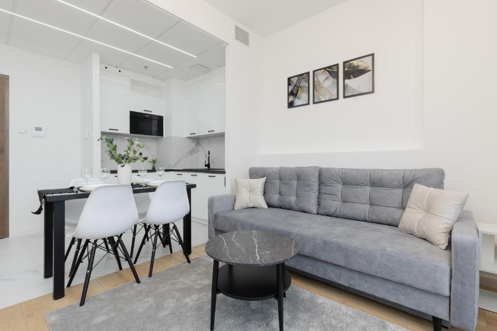 a living room with a couch and a kitchen at Cozy Apartments Warsaw Wola Kasprzaka by Renters in Warsaw