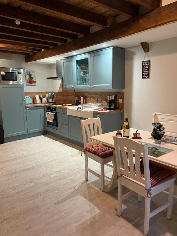 Toucy的住宿－Le Bourguignon，厨房配有蓝色橱柜和桌椅