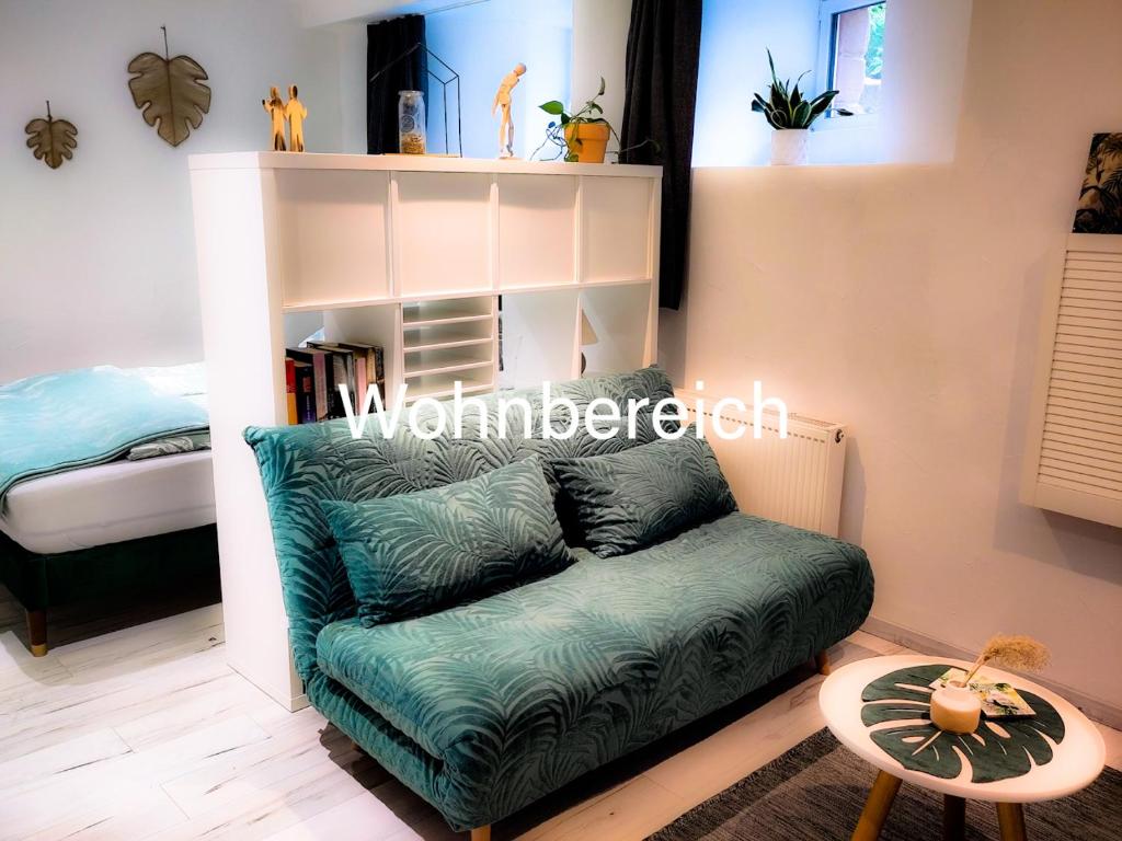uma sala de estar com um sofá verde e uma cama em Casa Viva - Separate, ruhig gelegene Wohnung em Quierschied