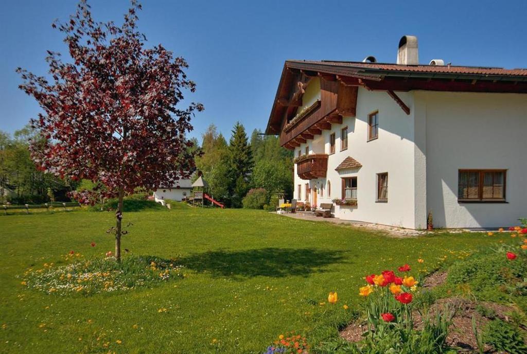 ein weißes Haus mit einem Garten mit einem Baum und Blumen in der Unterkunft Ruadlhof in Leutasch