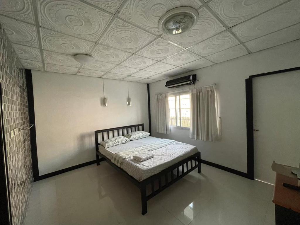 1 dormitorio con cama y techo en LSN Mansion, en Ban Na Song