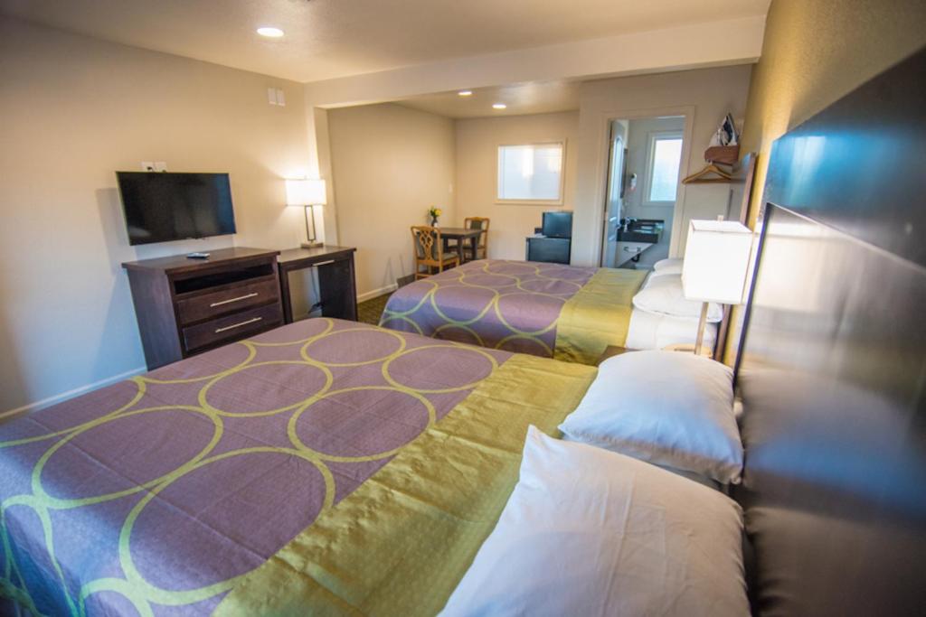 a hotel room with two beds and a flat screen tv at Budget Lodge Eugene - Airport in Eugene