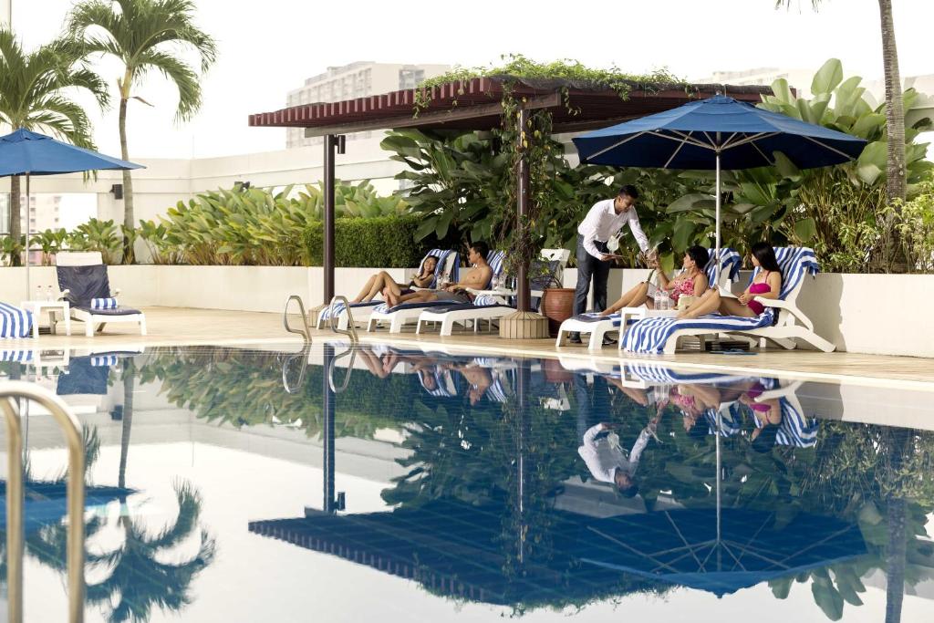 um grupo de pessoas deitadas em cadeiras ao lado de uma piscina em JEN Penang Georgetown by Shangri-La em George Town