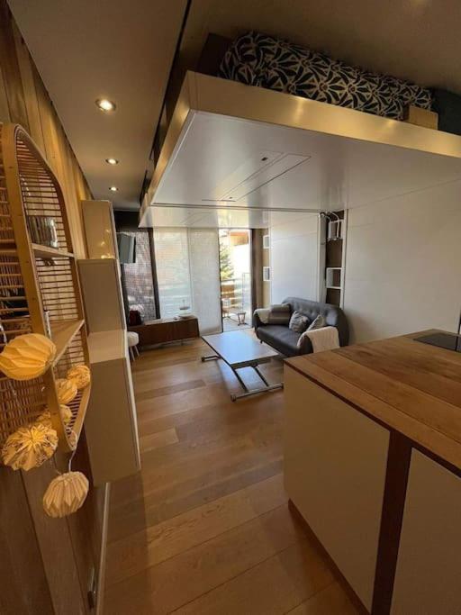 a kitchen and living room with a couch and a table at Studio cosy et moderne aux pieds des pistes in LʼHuez