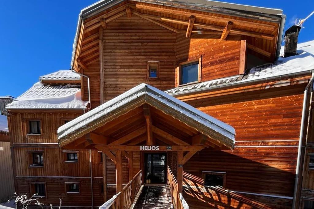 uma cabana de madeira com um telhado coberto de neve em Studio cosy et moderne aux pieds des pistes em LʼHuez