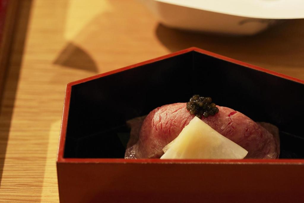 a red box with a piece of food in it at Waqoo Naritasanmonzen in Narita