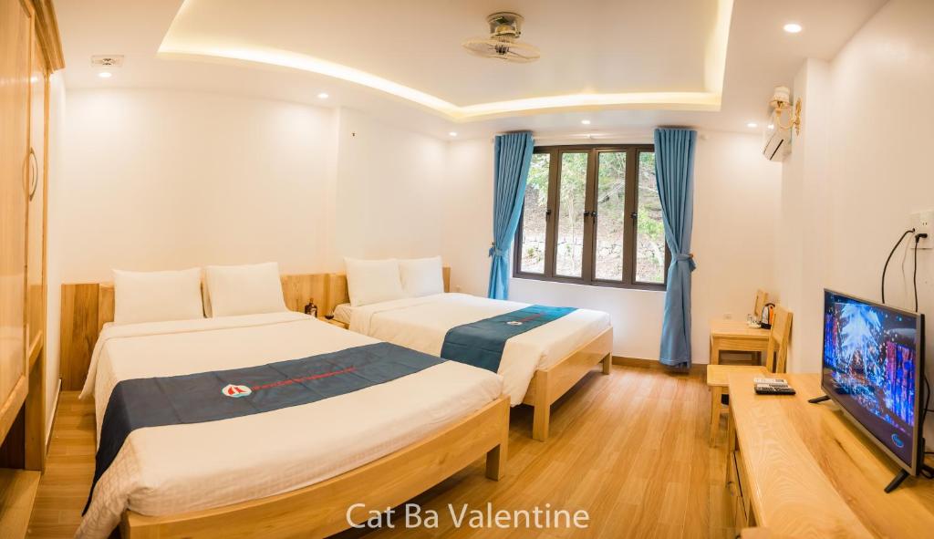 a hotel room with two beds and a tv at Cat Ba Valentine in Cat Ba