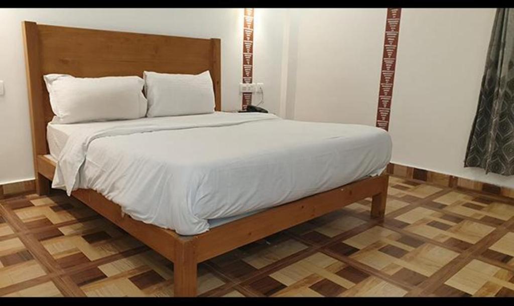 een bed met witte lakens en kussens in een kamer bij FabHotel Rudraksh Resort in Mussoorie