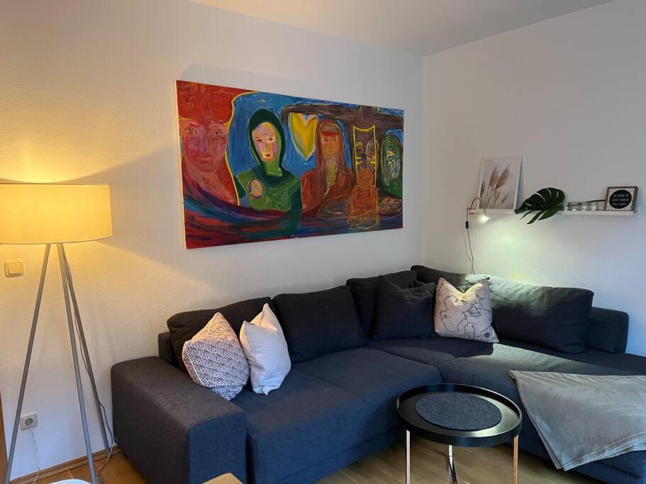 een woonkamer met een blauwe bank en een schilderij bij BELIEBT: Zentrales & ruhiges Innenstadtapartment in Halle an der Saale