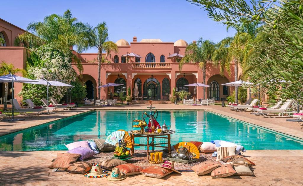 a swimming pool with a house and a resort at Palais Hassoun Marrakech in Oulad Snaguia