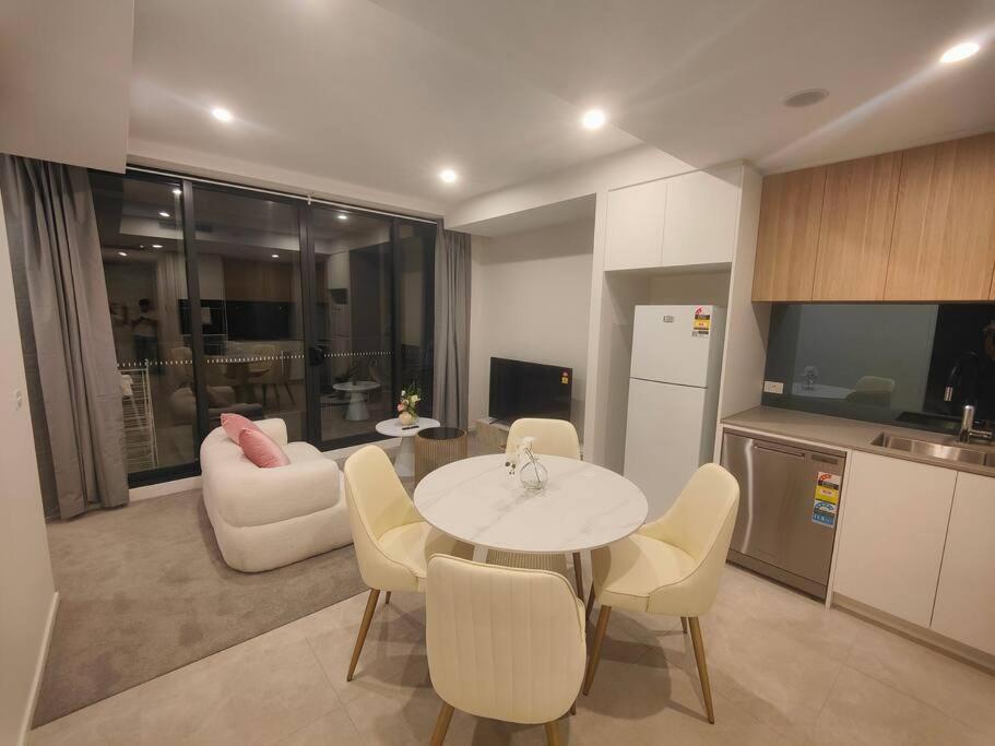 a kitchen and living room with a table and chairs at Brand New 2B1B Apt @ Inner North of Canberra in Canberra