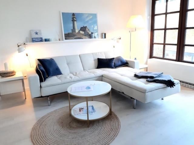uma sala de estar com um sofá branco e uma mesa em Nordseewölkchen 3 em Katingsiel