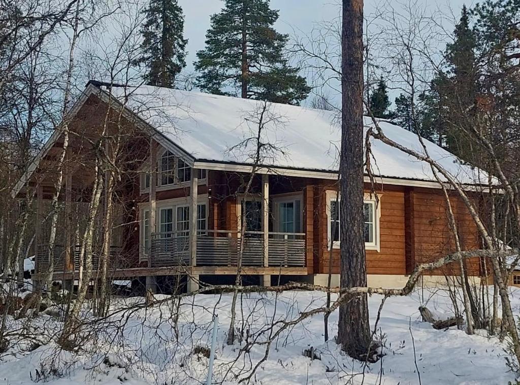 une cabane en rondins avec de la neige sur le toit dans l'établissement Villa Länsitaalo, à Kittilä