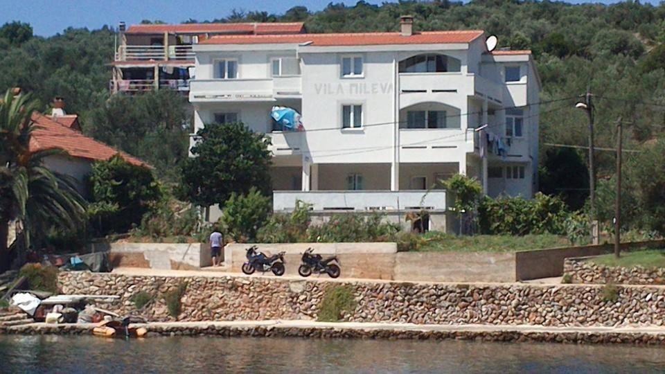 two motorcycles parked in front of a building next to the water at Apartments Vila Mileva in Rava