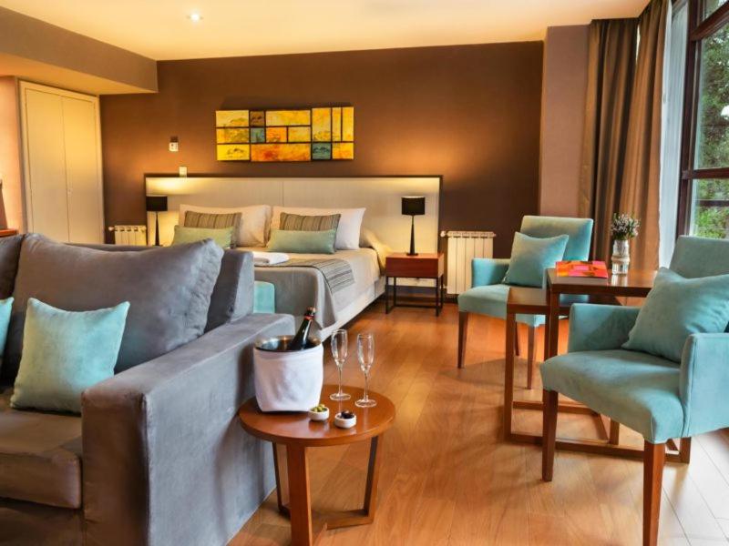a living room with a bed and a couch and chairs at Boutique Hotel & Spa Bosque del Nahuel in San Carlos de Bariloche