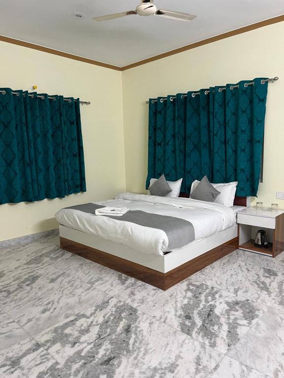 een slaapkamer met een groot bed en blauwe gordijnen bij Sunrise by Namastexplorer in Bhīm Tāl