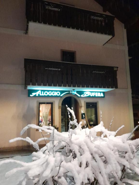 uma árvore coberta de neve em frente a uma loja em Alloggio Turistico Bufera em Roana