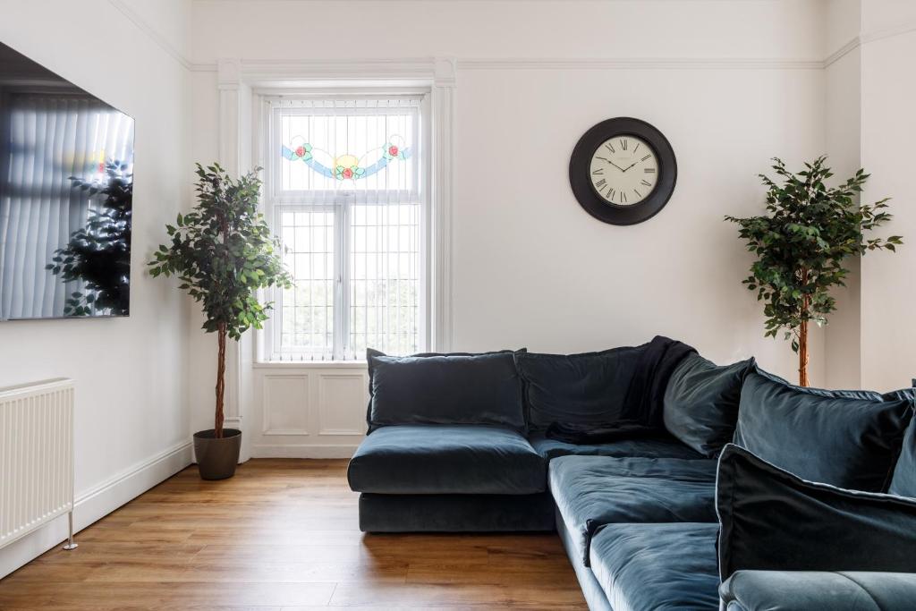 a living room with a couch and a clock on the wall at Beech Suite with 85 inch Cinema TV in Bradford