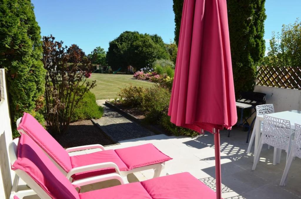sombrilla rosa y sillas en el patio en Gîte 3 avec piscine - plage 3kms, en Clohars-Carnoët