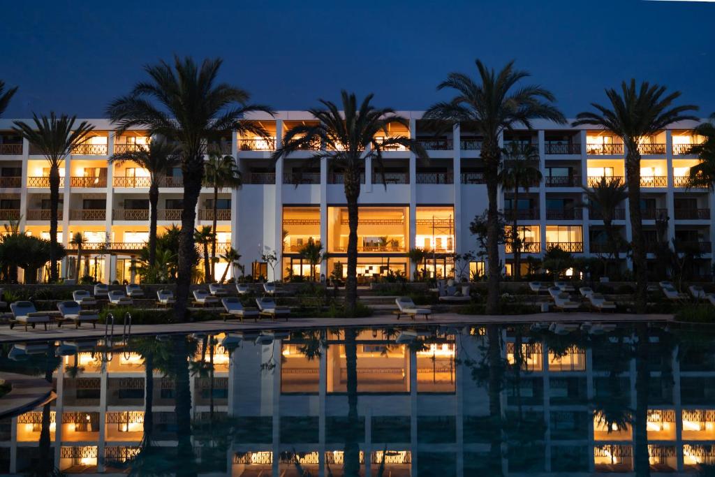 a hotel with palm trees in front of a pool at The View Agadir in Agadir