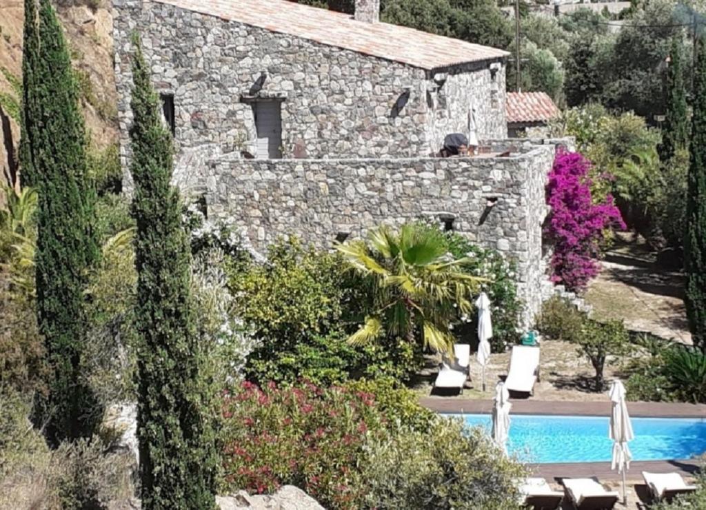 une maison en pierre avec une piscine dans un jardin dans l'établissement LUXURY 270M² HOUSE OF CHARACTER IN OLD STONES WITH HEATED POOL, NEAR CALVI, à Calenzana