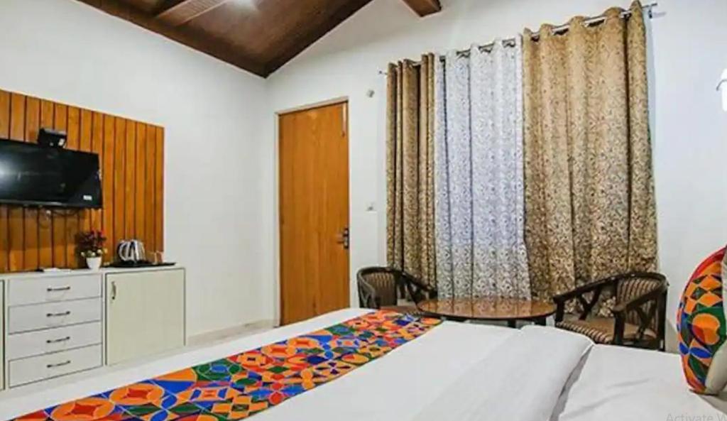 a bedroom with a bed and a table and a tv at Corbett Jungle Breeze Resort in Rāmnagar